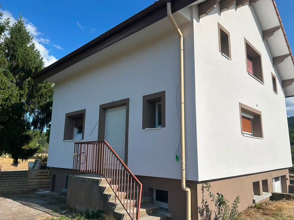 Isolation thermique par l'extérieur à Anould — maison terminée, encadrements de fenêtres contrastés