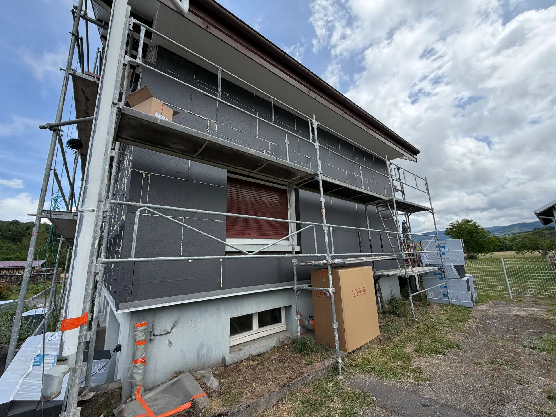 Isolation thermique par l'extérieur à Anould — façade couverte de panneaux isolants gris, échafaudage en place