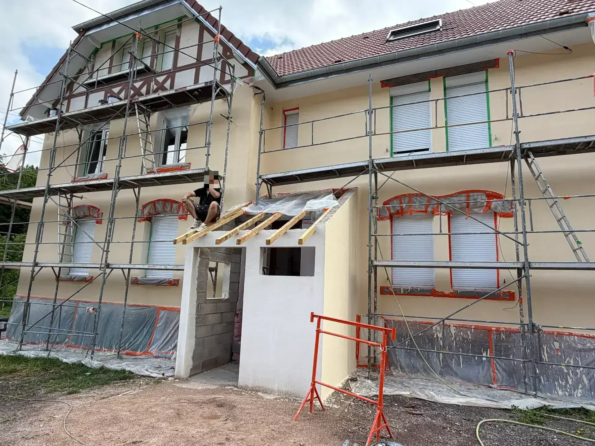 Ravalement de façade à Senones — façade en cours d'enduit, fenêtres protégées et auvent en construction